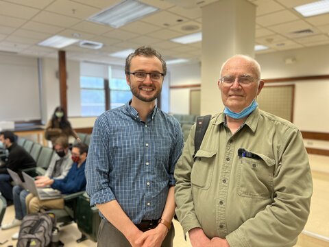 Nick Jackson, left, stands next to Remec in a Noyes classroom with students sitting at desks behind them.