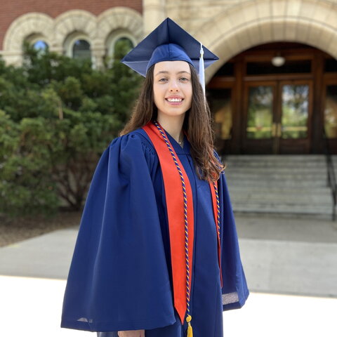 Portrait of Morgan Kennebeck in cap and gown in front of Noyes entrance