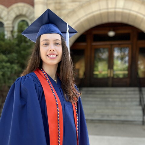 Photo of Morgan in a cap and gown in front of Noyes