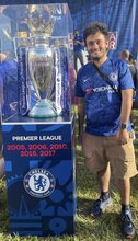 Sagnik Chakribarti standing next to a case holding a professional soccer league trophy