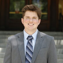 Portrait of Seth Klaine in a suit jacket and tie standing in front of Noyes Laboratory's main entrance.