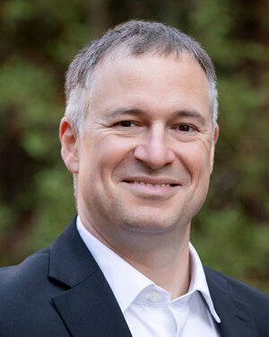 Head shot of Liviu Mirica with a blurred outdoor background.