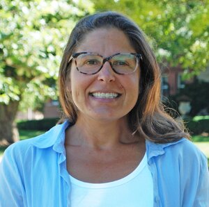 Head shot of Lisa Olshansky outdoors with green leaves of trees in the background