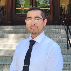 Portrait of Carlos Juarez-Yescas standing in front of the steps to the main entrance to Noyes Laboratory.