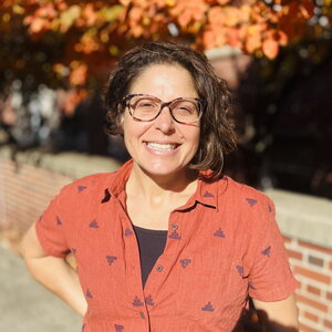 Lisa Olshansky standing in front of a low brick wall and tree outside Noyes Laboratory