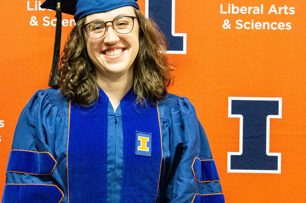 Sophie McClain in a cap and gown in front of an orange background