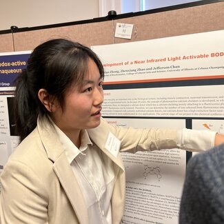 Zhuoran Zhong stands in front of her research poster as she explains her research.